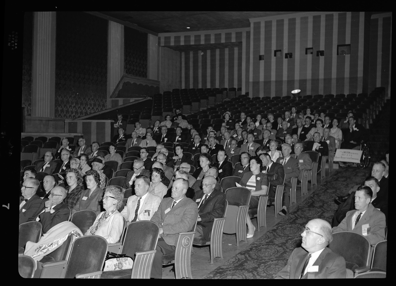 Crowd of unidentified men and women sitting in rows in a room at the Rotary International Club Convention.
