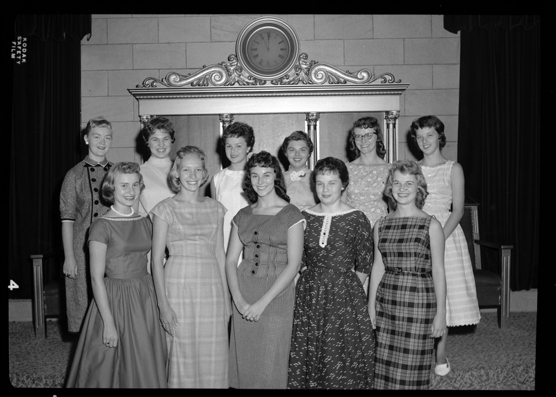 A group of women stand together in two rows for a photo for the Benevolent and Protective Order of Elks Queen Candidates. All of the women are well dressed and smiling at the camera.