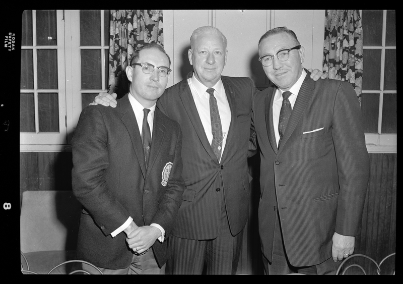 Photo of three men standing together, posed for a picture for an event for the Gyro District Governor. They are all dressed in suits.