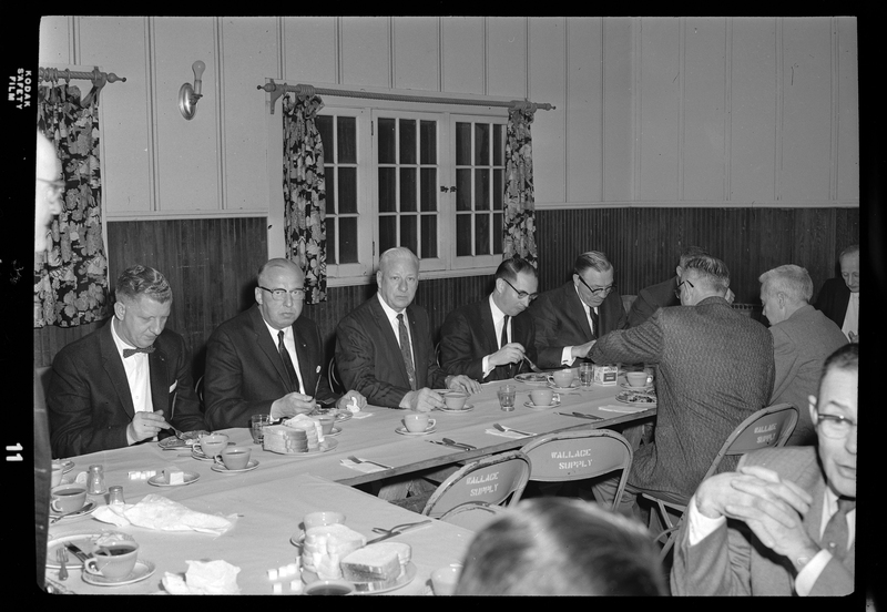 Photo of a group of men seated at tables and eating at an event for the Gyro District Governor.