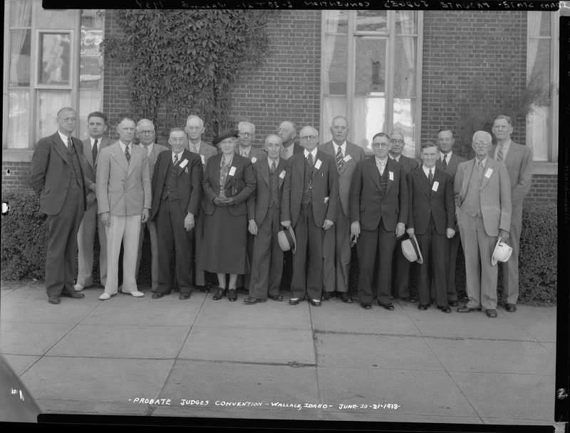 Photo of a group of men and a woman standing outside of a building for the Idaho State Probate Judge Convention. Everyone is dressed formally and standing together to pose for the photo.