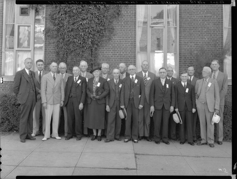 Photo of a group of men and a woman standing outside of a building for the Idaho State Probate Judge Convention. Everyone is dressed formally and standing together to pose for the photo.