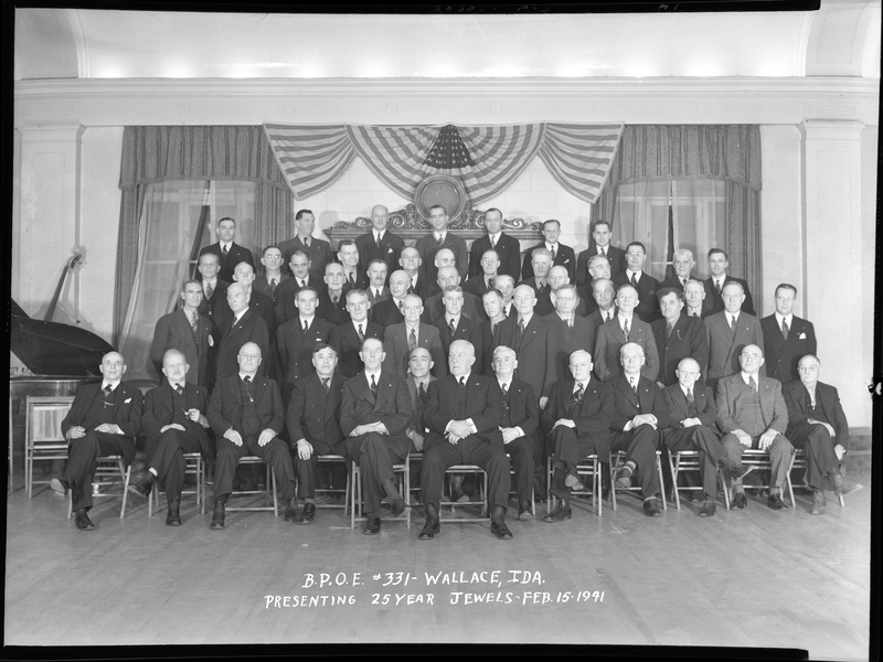 Men from Benevolent and Protective Order of Elks #331 sitting together for event "Presenting 25 Year Jewels." They are standing in rows with the front row seated, and they are all wearing suits.