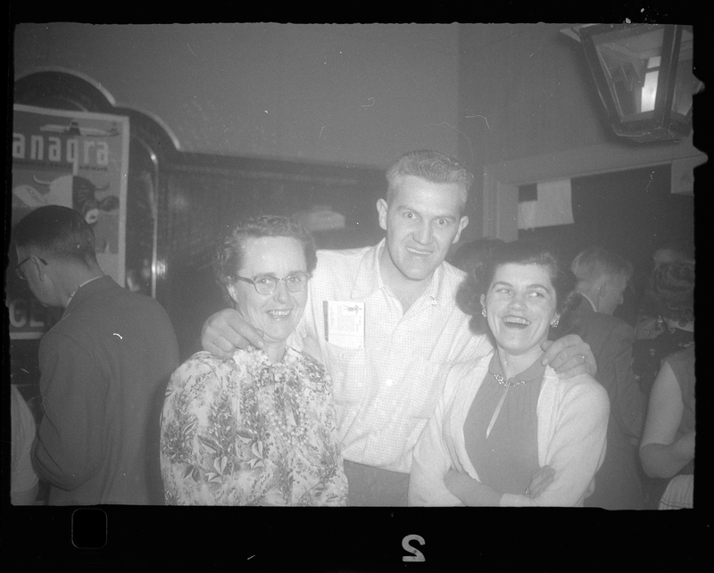 Photo of a man with two women at Rotary Party. The man has his arms around the women and they are all smiling at the camera.