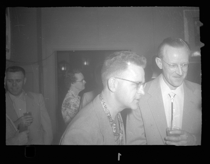 Candid photo of men at a Rotary Party. They are talking to someone out of view of the camera.