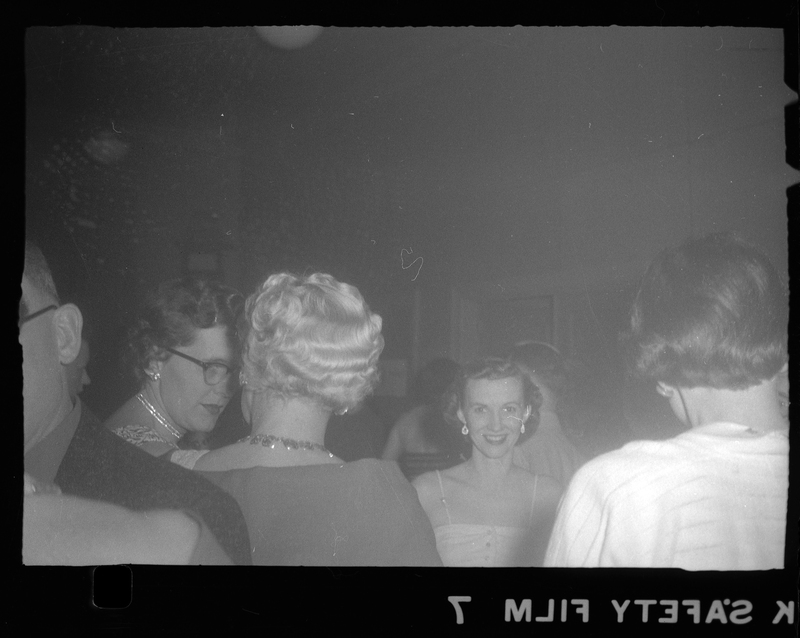 Photo of some people at a Rotary Party. Most people are looking and/or facing away, but one woman is looking at and smiling at the camera.