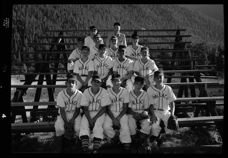 Group photo of the Babe Ruth all-star baseball team members sitting together on a set of bleachers. They are wearing matching uniforms and some have their gloves on.