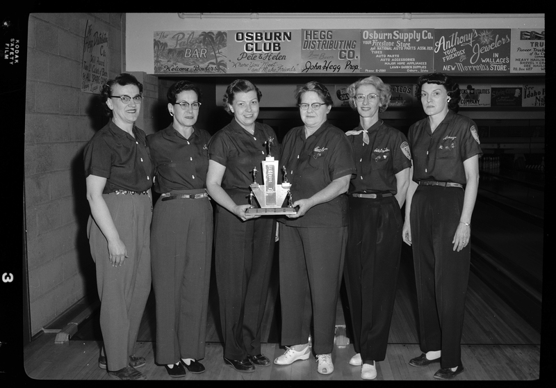Photo of the Scoops bowling team posing together with a trophy. There are six women present.
