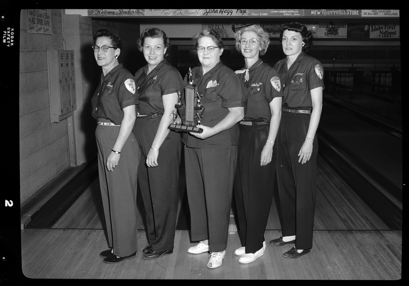 Photo of the Scoops bowling team posing together with a trophy. There are five women present.
