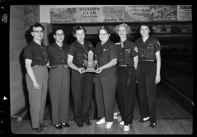 Photo of the Scoops bowling team posing together with a trophy. There are six women present.
