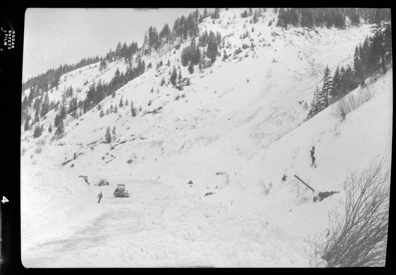 Photo of the aftermath of an avalanche in Burke, Idaho. A few snowplows can be seen in the background in the snow.