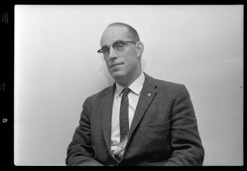 Photo of a man wearing a suit and glasses. Possibly Bill Featherstone.