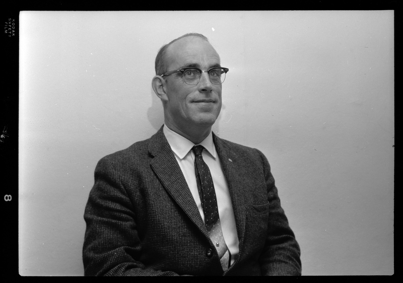 Photo of a man wearing a suit and glasses. Possibly Bill Featherstone.