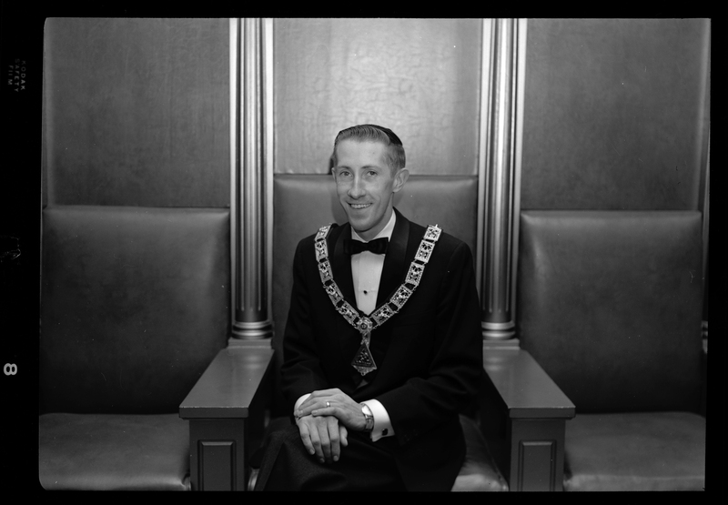 Photo of the Exalted Ruler of the Benevolent and Protective Order of Elks, Bob Wheeler. He is sitting in a chair, wearing a tuxedo, and a pendant.