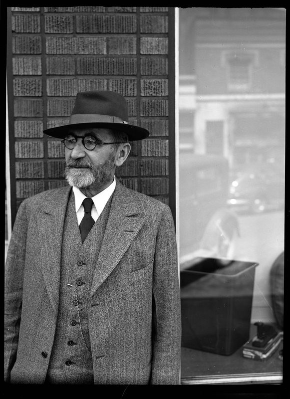 Photo of Frank Pfirman standing outside in a suit and hat.