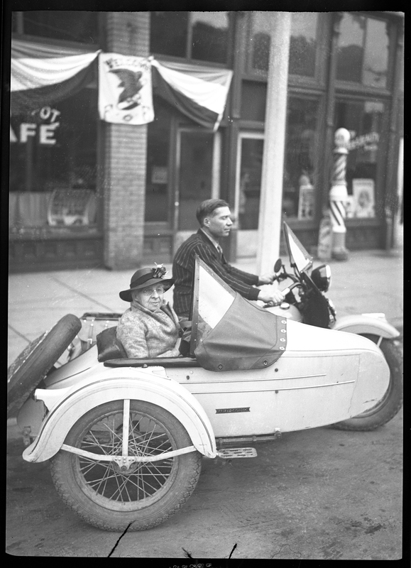 Mary Blasius and Sam Joe on their motorcycle, Sam on the bike's seat and Mary in the sidecar.  1,000 mile trip to Wallace, Idaho for Eagles State Convention, likely referring to the Fraternal Order of Eagles.