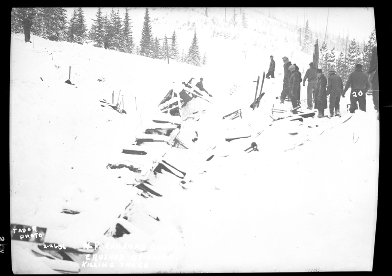 A group of people stand to the side of a train wreck after an avalanche hit it on the Northern Pacific Railroad. Three people died.
