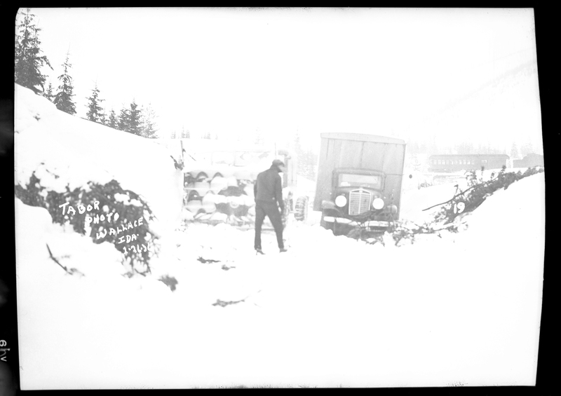 A person standing in the snow with a car in the background responding to a train wreck after an avalanche hit it on the Northern Pacific Railroad. Three people died.