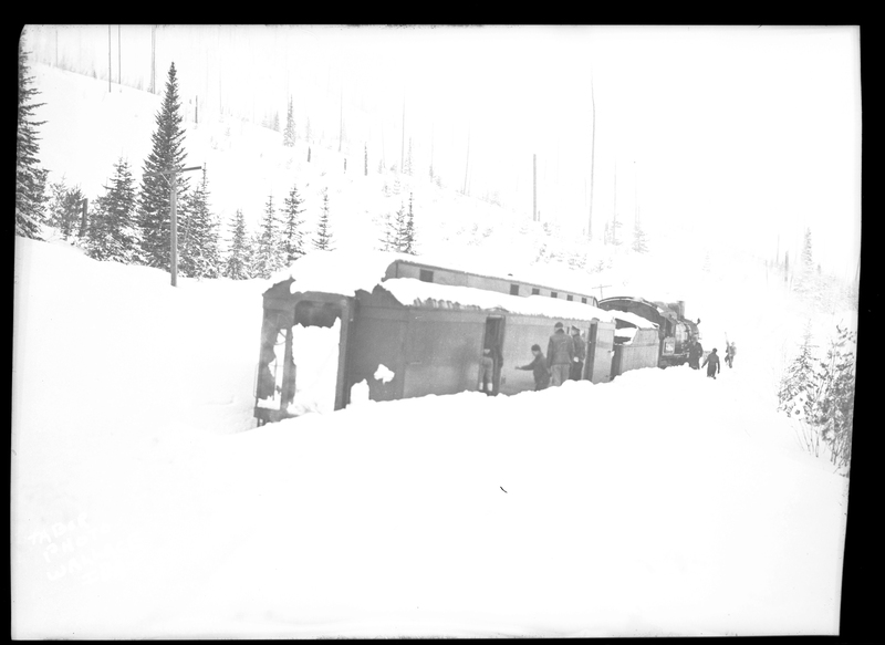 A handful of people inspect some train cars that are not knocked over after an avalanche hit it. Three people died.