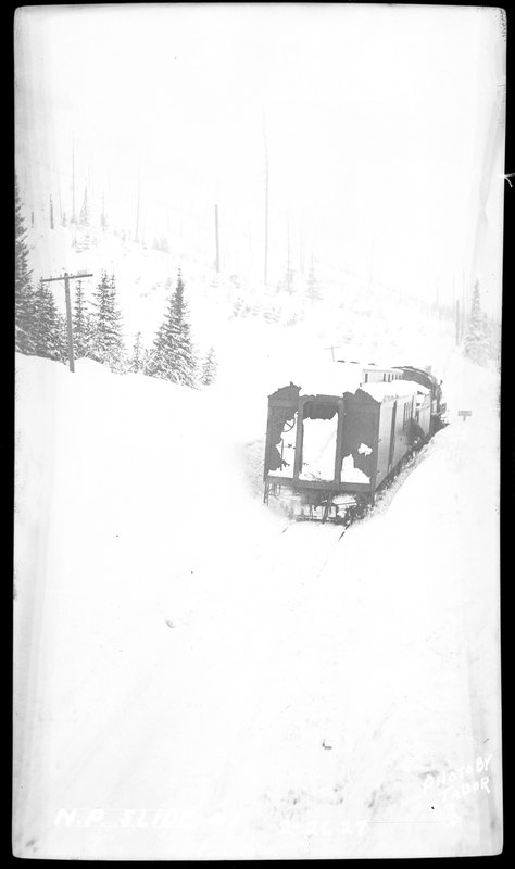 Photo of a train car, still upright, after an avalanche hit it on the Northern Pacific Railroad. It's covered in snow, but appears to still be on the tracks. Photos say that three people died.