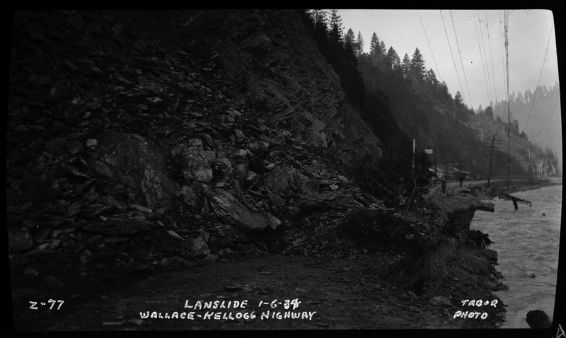 Landslide on the Wallace-Kellogg highway, as written on the photo. The landslide is completely covering the road, and spills into the river off the side of the road. Previously described as Rock slide, Rocky Point, 1 mile west of Wallace, Idaho."