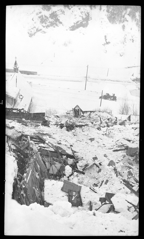 Photo of what is likely destroyed buildings in Burke, Idaho as a result of an avalanche. There is a snowplow visible in the distance.