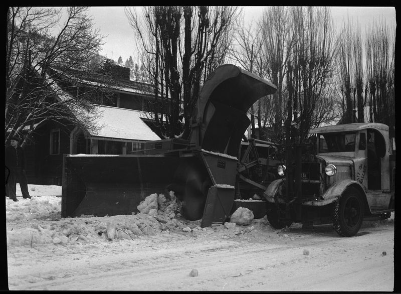 Photo of the front of a snow loading truck in Wallace, Idaho. The truck is on the side of the road, but it does not appear to be operating when the photo was taken.