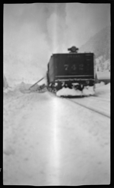 Blurry, unfocused photo of a train component on the tracks in the snow. It appears to be plowing snow.