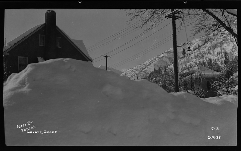 Unidentified building behind a large snow pile. Building could be Wallace, Idaho's City Hall, United States Post Office, or Standard Stations Inc.