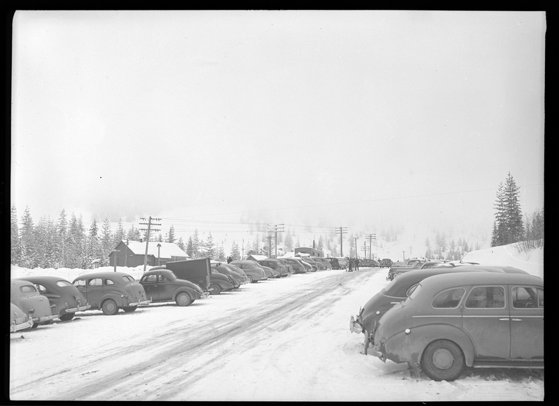 Cars parked outside in the snow for a ski tournament.