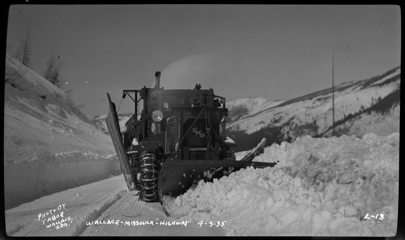 A snowplow moves towards the photographer while actively plowing snow from the road.