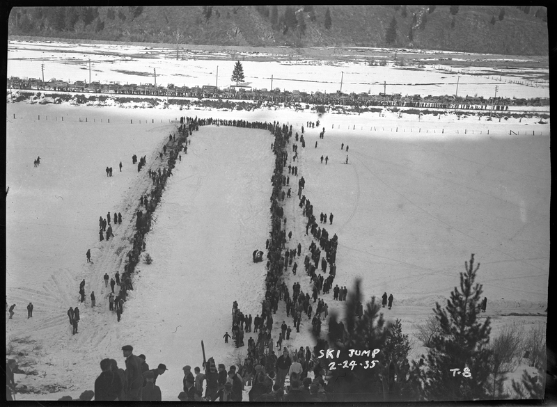 Photo of a crowd of spectators at a ski jump event at Lookout Pass. They are lined up around the base of the landing area.