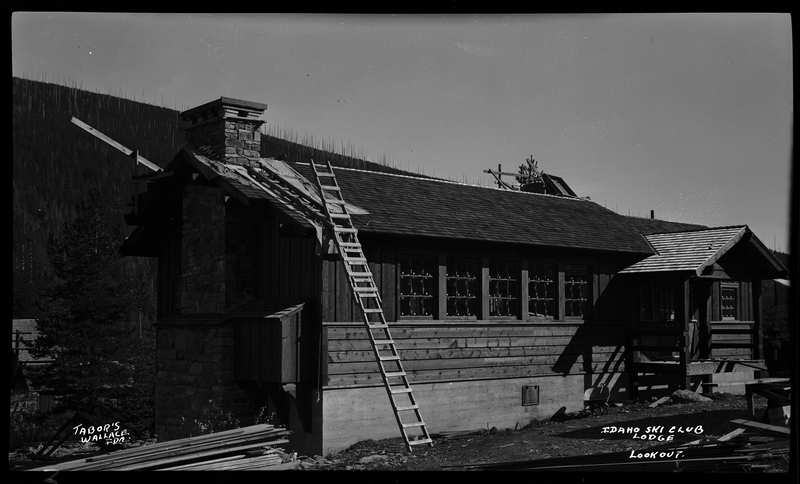 Photo of the Idaho Ski Club Lodge at Lookout Pass. There is a ladder leaning against the roof of the building and it appears that there is ongoing construction happening to the building.