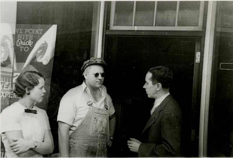 Three people, including George Tabor on the far right, talk while standing in front of a building.