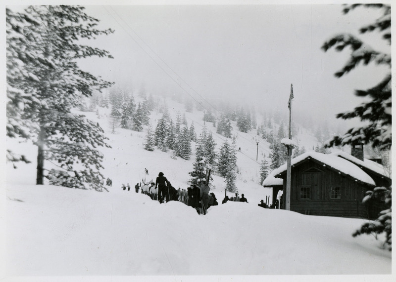 Several people make their way towards Lookout Pass. One of them appears to have ski poles and many of them are carrying skis.