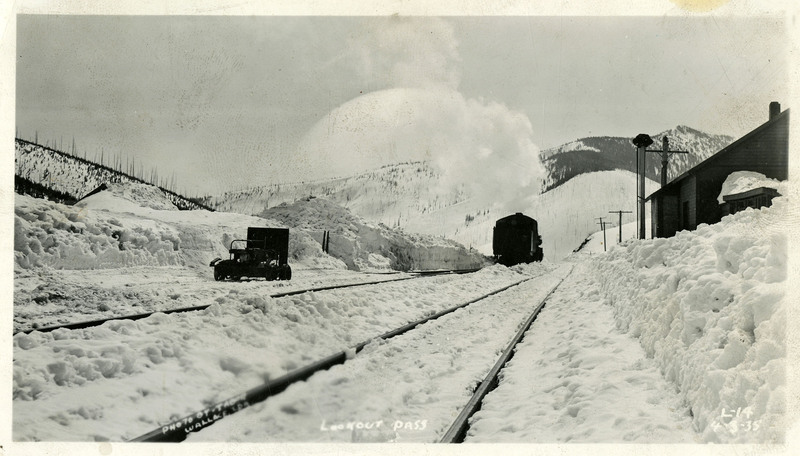 A shot of a railroad near Lookout Pass. A train can be seen on the tracks, and an abundant amount of snow is covering the surrounding area.