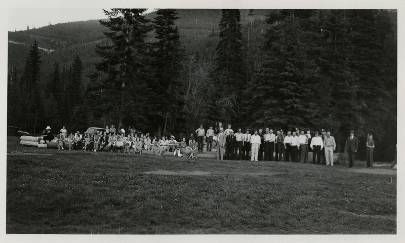 People in plainclothes, mostly women and children, sit in a crowd on the left while men in uniform stand on the right. The handwriting on the photo lists several names: [illegible], Lenney, Glen, Mayor, [illegible], and [illegible].