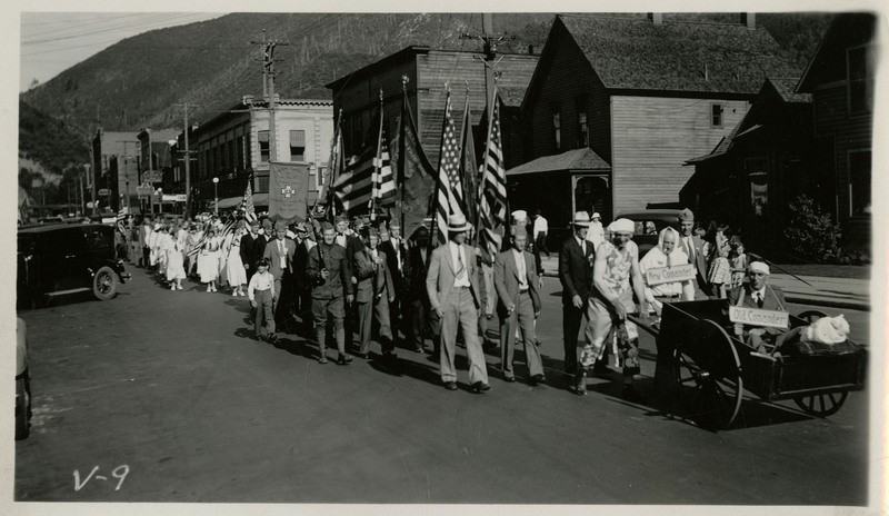 A collection of people march in the Veterans of Foreign Wars State Convention parade. Several groups, including the Shoshone Auxiliary to Post 1675 and a military color guard, are visible.
