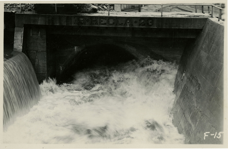 Water rushes through a tunnel underneath a bridge during the Wallace flood. The bridge appears to read "19-HECLA-23."