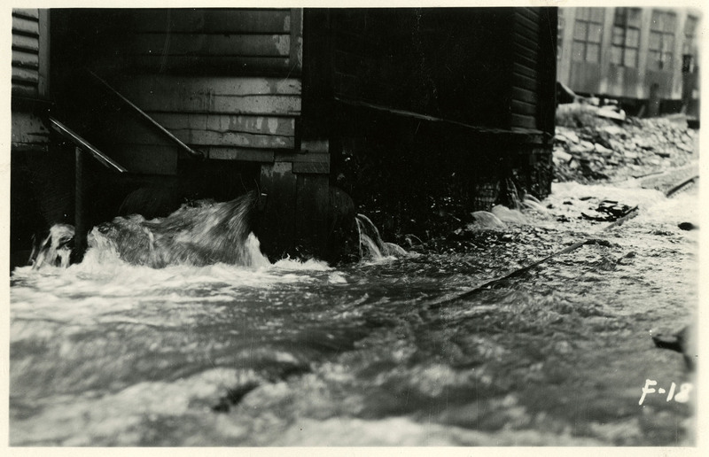 Water rushes out from underneath a building during the Wallace flood.
