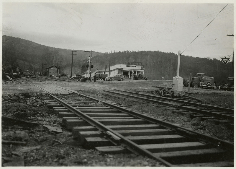A shot of the railway after most of the plant debris had been removed. Several cars are parked near the tracks and a Shell station.