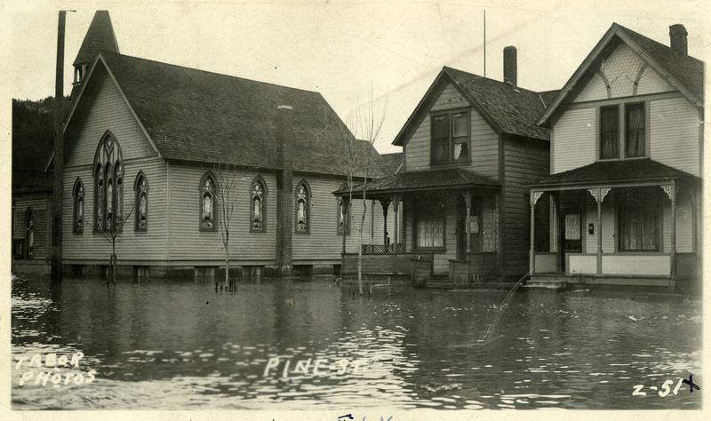 Calm floodwaters reach the porches of houses and a church located on Pine Street during the Wallace flood.