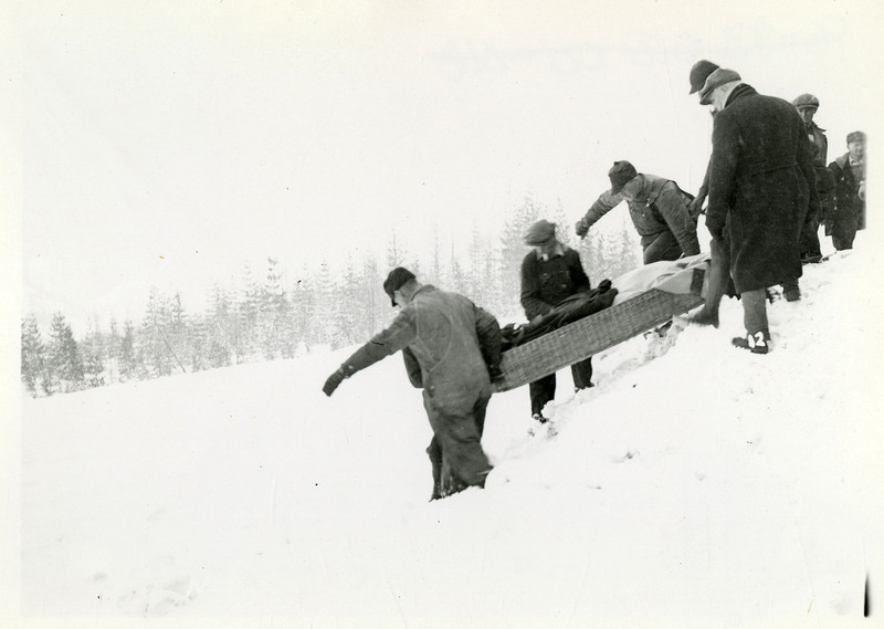 A group of people carry a person on a stretcher down a snowy hill after the Northern Pacific slide.