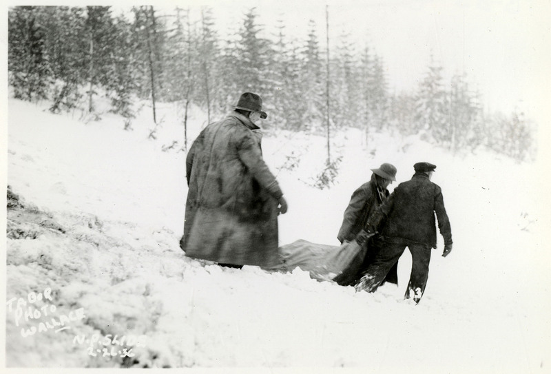 Three people drag something down a snowy hill after the Northern Pacific slide.