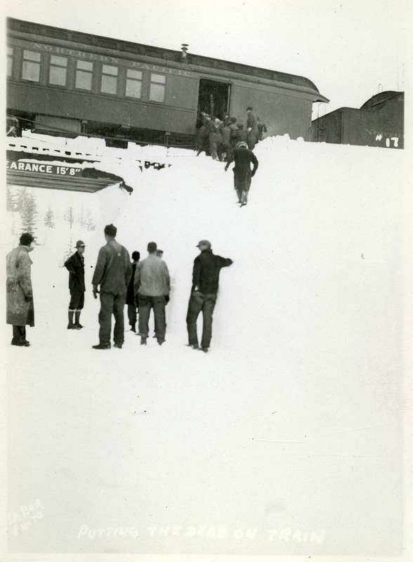 A group of people walk up a snowy hill to a train after the Northern Pacific slide.