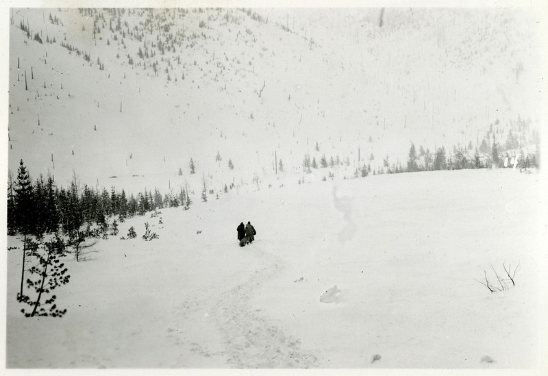 Two people drag what appears to be a body bag down across a snowy field after the Northern Pacific slide.