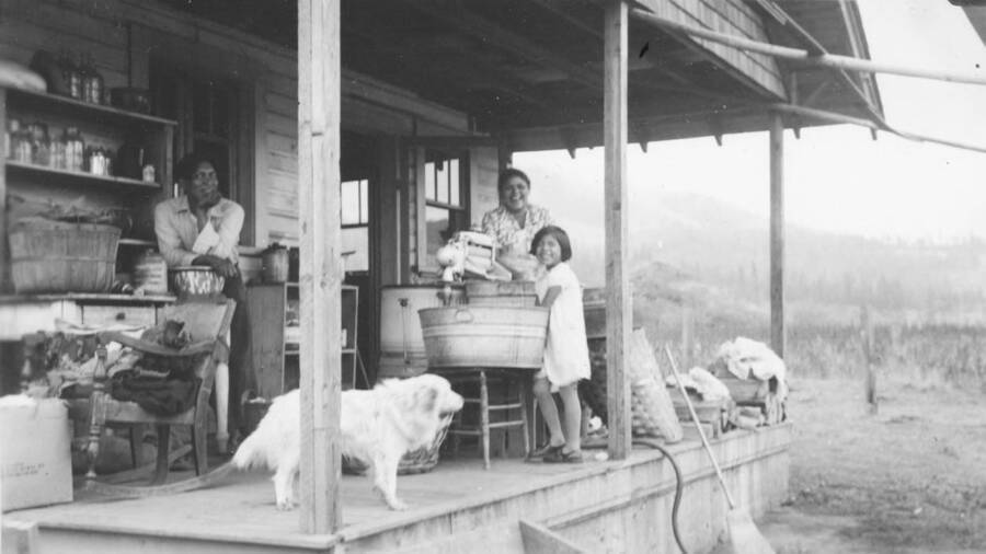 Photo caption: 'Wash day, is done in the modern way, at the Sam Pablo back porch, Kamiah.' This image is part of a report regarding farm organizations among tribes in Northern Idaho and the CCC-Indian Division.