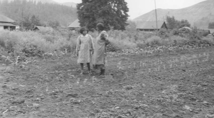 Photo caption: 'Mabel Lowry and June Kipp have us look at their gardens.' This image is part of a report regarding farm organizations among tribes in Northern Idaho and the CCC-Indian Division.
