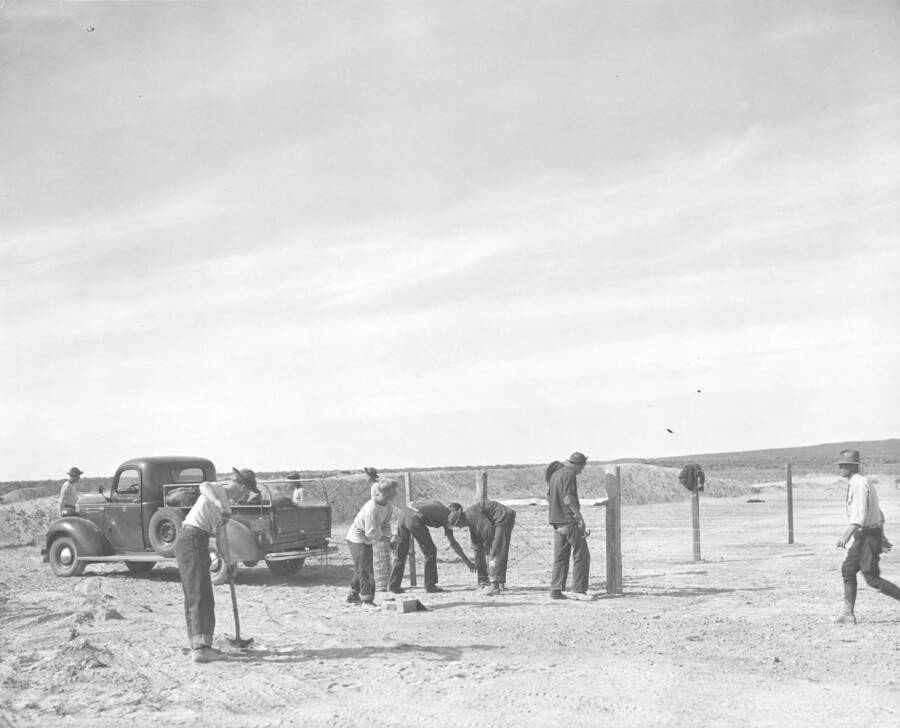 CCC workers from Mountain Home Camp G-99 work on fence. Pickup truck in background. Image part of CCC-Idaho Indian Division.