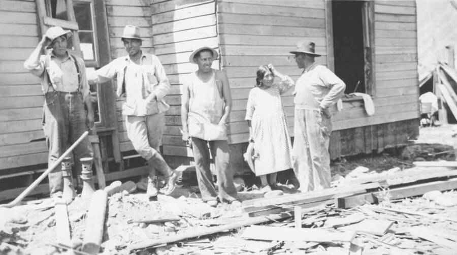 Photo caption: 'The work crew gets to work. Levels the house.' This image is part of a report regarding farm organizations among tribes in Northern Idaho and the CCC-Indian Division.